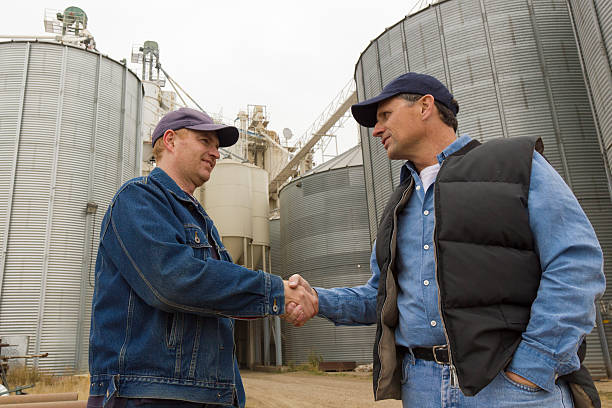 an image from the farming industry of two farmers shaking hands at a grainery. an image from the farming industry of two farmers shaking hands at a grainery.